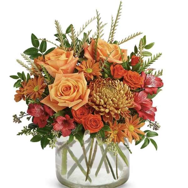 Orange and red mixed flower arrangement in a clear glass vase