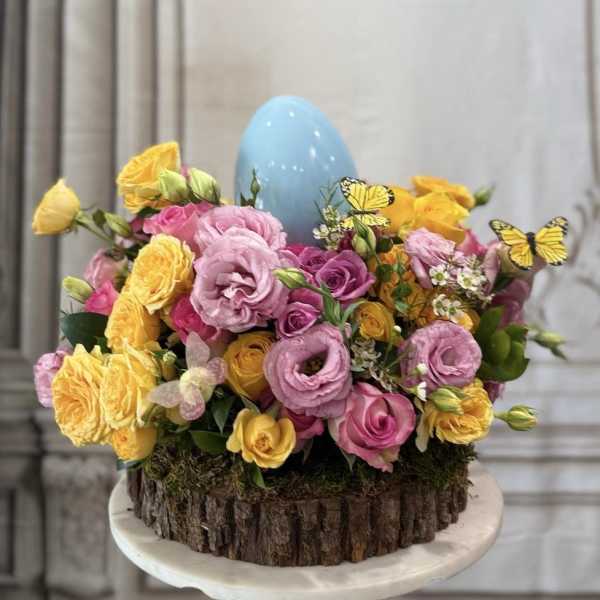 Pink and yellow roses arranged around a blue egg centerpiece