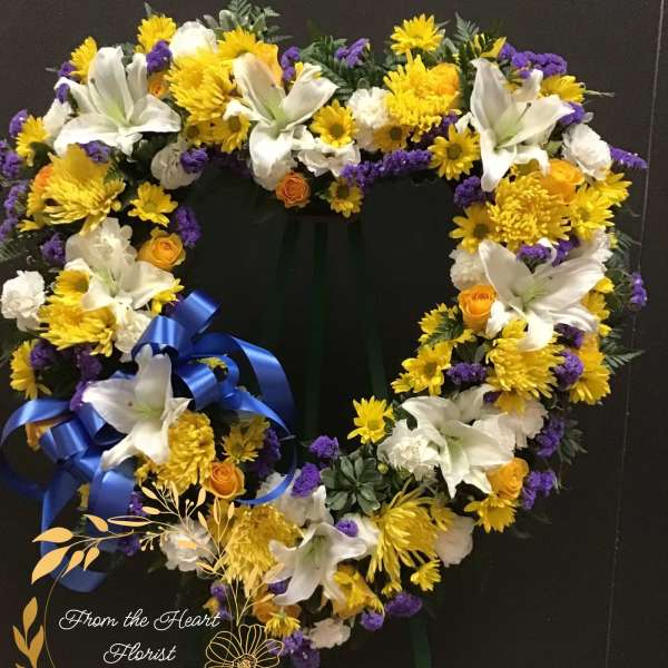 Heart-shaped floral wreath with white lilies, yellow blooms, and purple accents