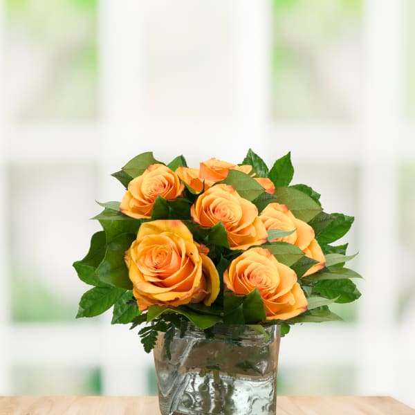 Orange roses arranged in a clear glass vase