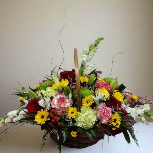Basket arrangement of mixed red, yellow, white, and green flowers