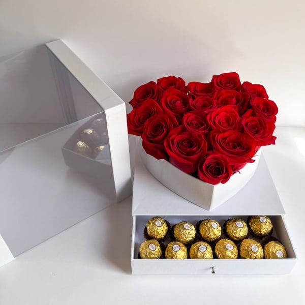 Heart-shaped box of red roses with a tray of gold-wrapped chocolates