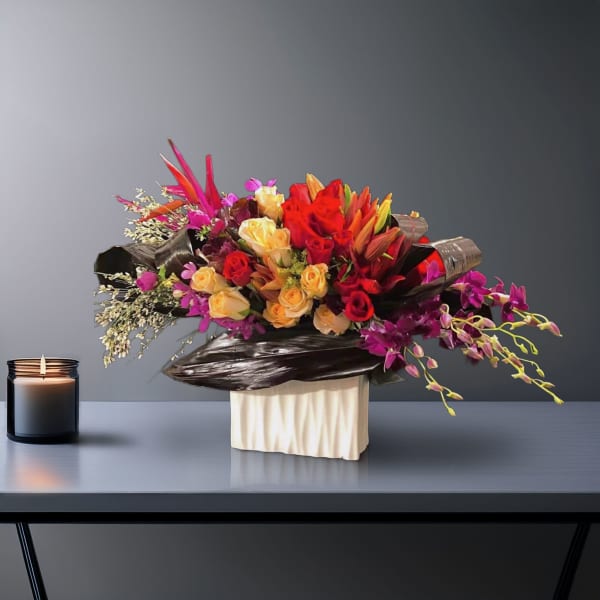 Bright mixed bouquet with roses, lilies, and orchids in a white vase