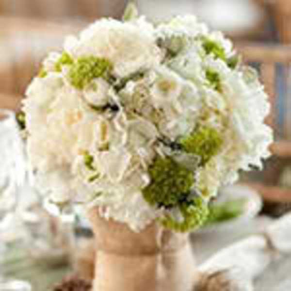 Round bouquet of white blossoms with green accents and a wrapped handle