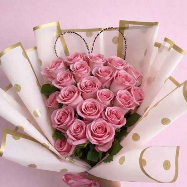 Pink rose bouquet wrapped in white paper with gold dots