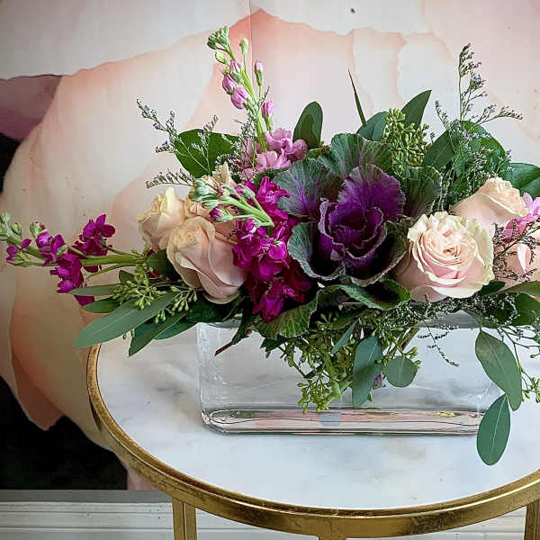 Pink and purple floral arrangement in a clear rectangular vase