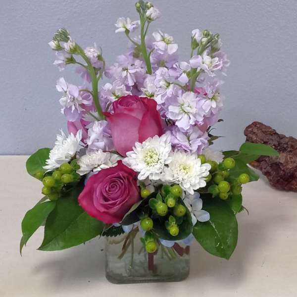 Pink roses and white flowers arranged in a clear glass vase