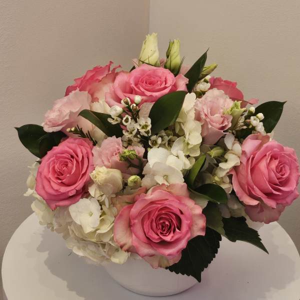 Pink roses and white hydrangeas arranged in a white bowl vase