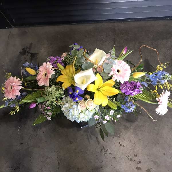 Long floral arrangement with pink gerberas, yellow lilies, and white calla lilies