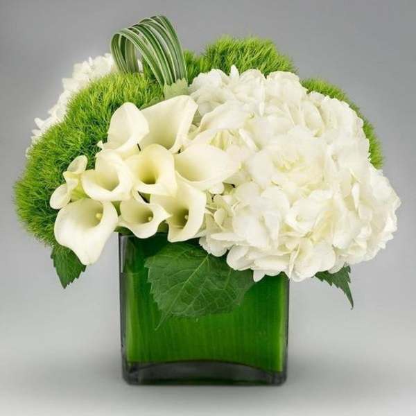 White calla lilies and hydrangea in a green glass vase