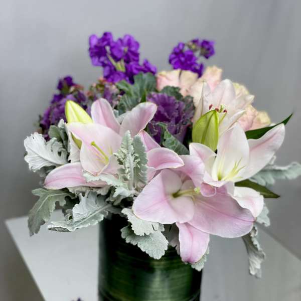 Pink lilies and purple flowers in a dark green vase