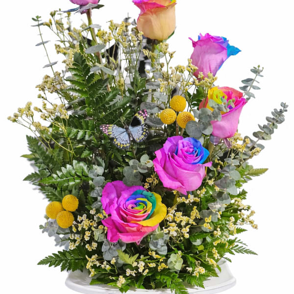 Rainbow-tinted roses in a white vase with a butterfly decoration