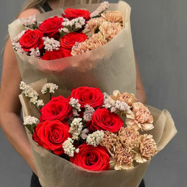 Two bouquets of red roses and peach carnations wrapped in brown paper