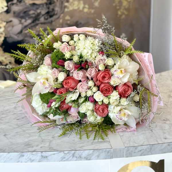 Bouquet of pink and white roses with white orchids wrapped in pink paper
