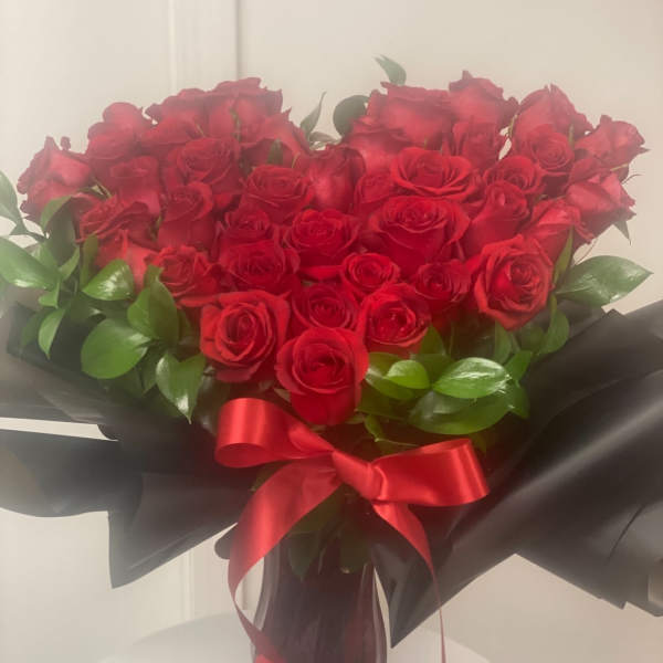 Bouquet of red roses wrapped in black paper with a red ribbon