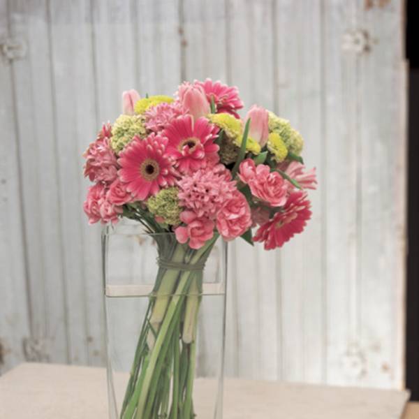 Pink mixed flowers arranged in a clear rectangular vase