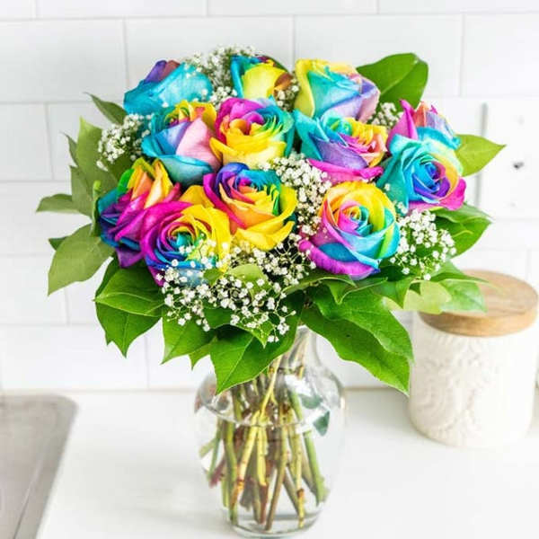 Bouquet of rainbow-colored roses in a clear glass vase