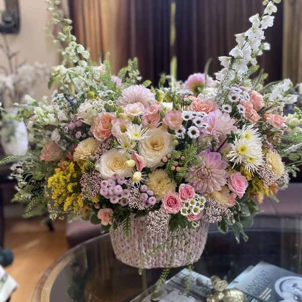 Large pastel flower arrangement in a woven basket