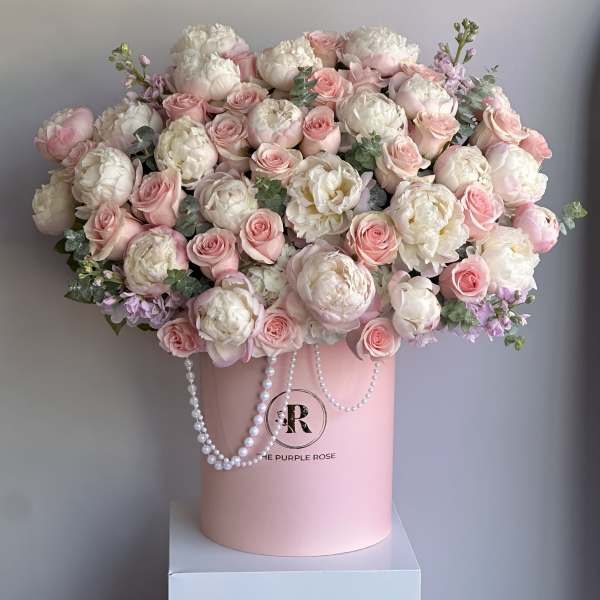 Large arrangement of white peonies and pink roses in a pink hatbox with pearl garlands.