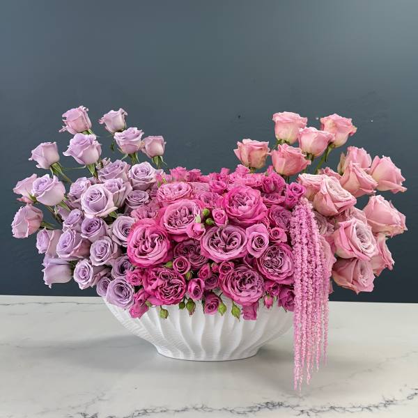 Pink and lavender roses arranged in a white vase