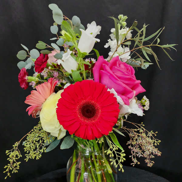Mixed bouquet in a glass vase with pink, red, white, and peach flowers