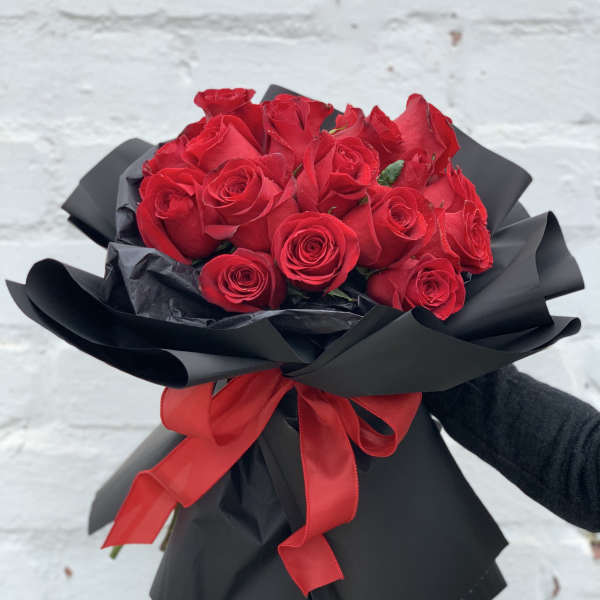Bouquet of red roses wrapped in black paper with a red ribbon