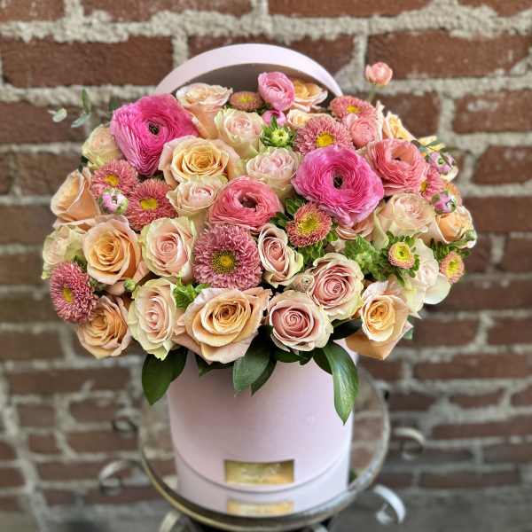 Pink and peach roses with small pink daisies in a round hat box