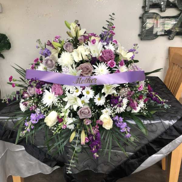 Large purple and white floral arrangement with a ribbon reading Mother
