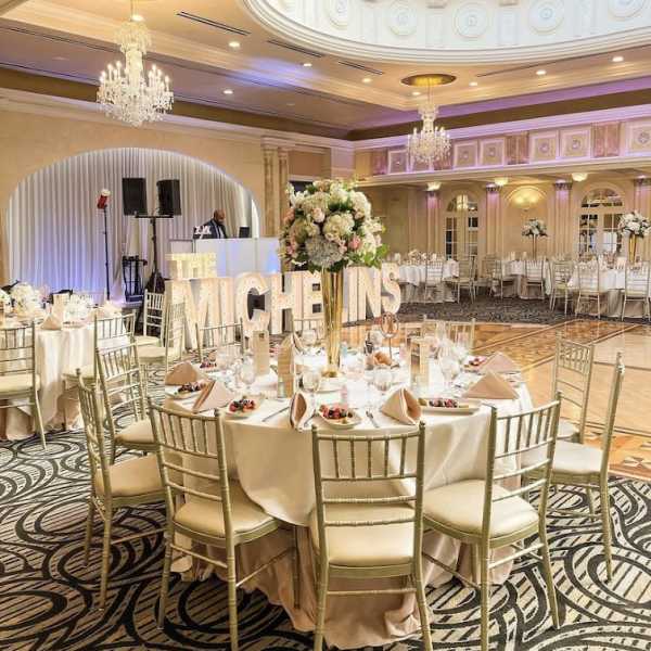Floral centerpieces on round banquet tables in a decorated ballroom