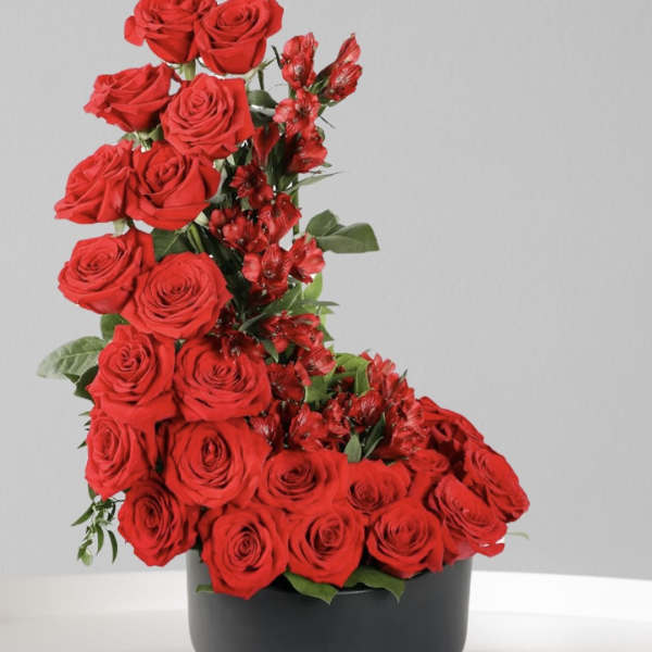 Red roses and red alstroemeria arranged in a black round box