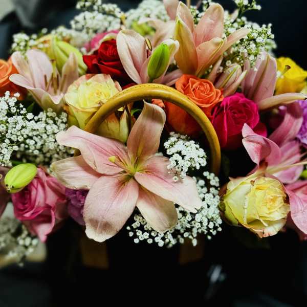 Mixed bouquet of lilies and roses in a black handbag-style container