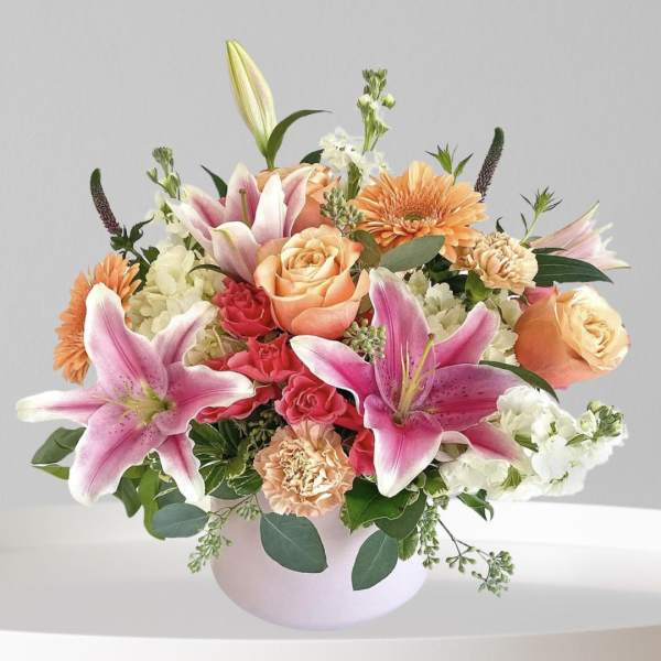 Pink lilies and peach roses in a round vase