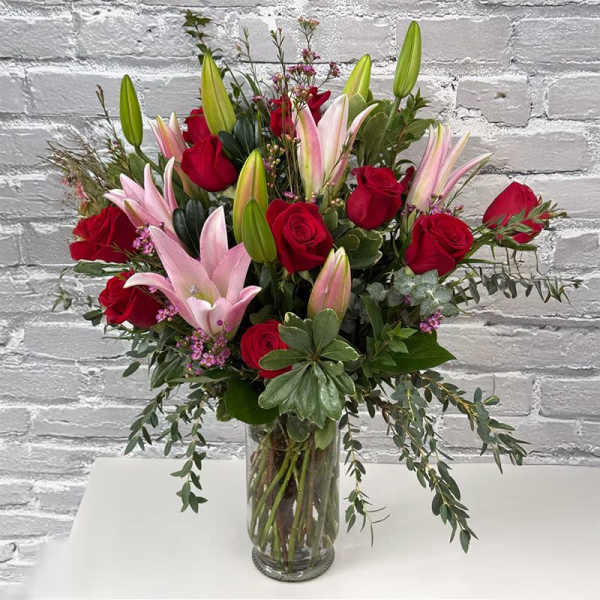 Red roses and pink lilies arranged in a clear glass vase