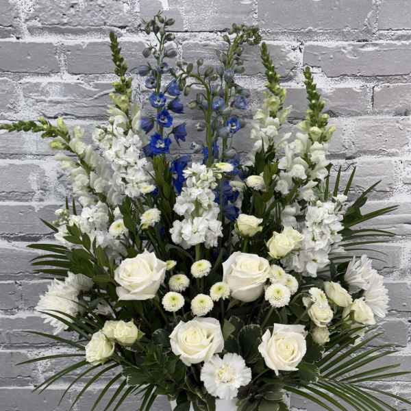 White roses and blue delphinium in a white urn vase