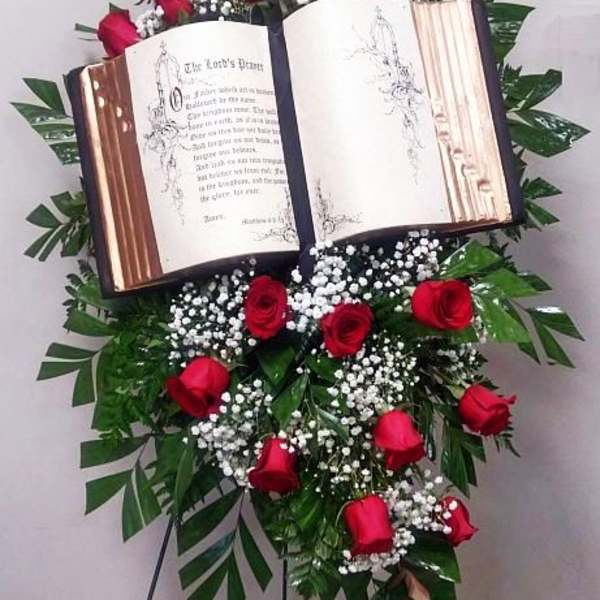Standing floral tribute with red roses around an open book display