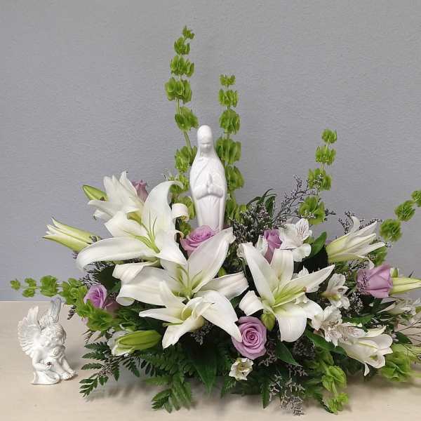 White lilies and lavender roses arranged around a small white statue