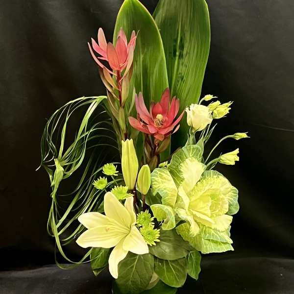 Tropical floral arrangement with pink and cream blooms in a vase