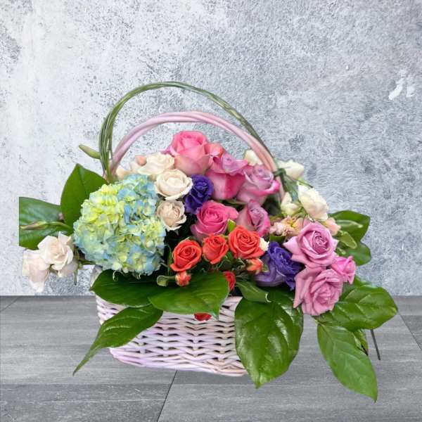 Basket of multicolored roses with a blue hydrangea bloom