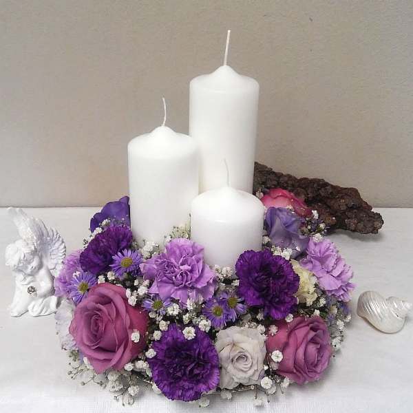 Purple floral candle centerpiece with three white pillar candles