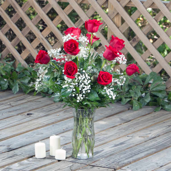 Red roses in a clear glass vase with white filler flowers