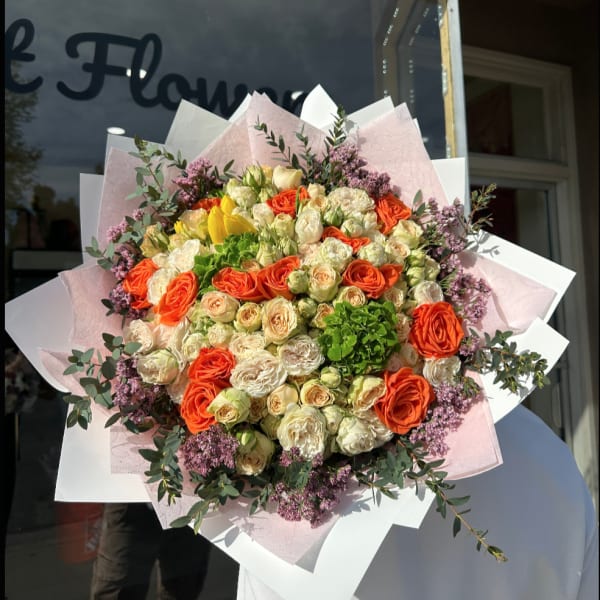 Large bouquet of orange and cream roses with pink filler flowers