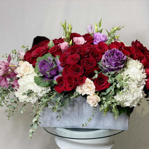Large arrangement of red roses with white and purple flowers in a gray box