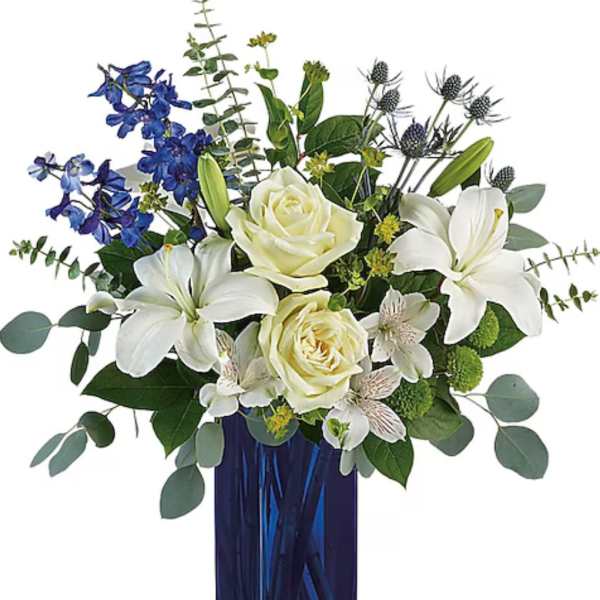 White lilies and roses in a blue glass vase with blue flowers