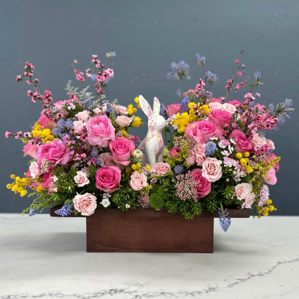 Pink rose arrangement in a wooden box with a ceramic rabbit figurine