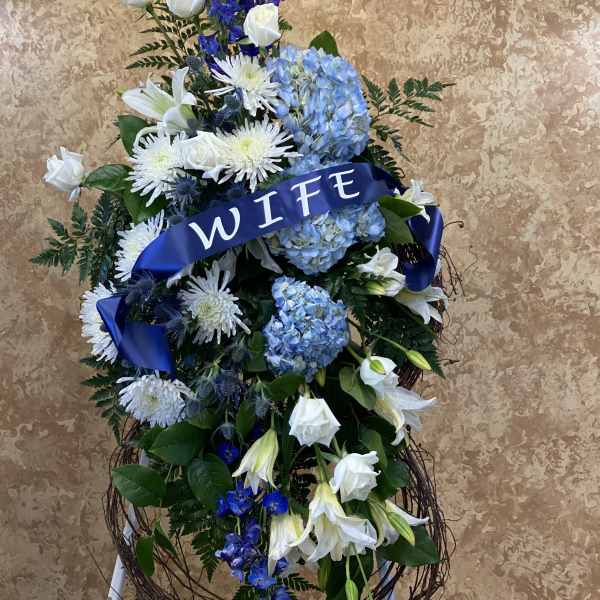 Large blue and white floral standing spray with a ribbon reading WIFE