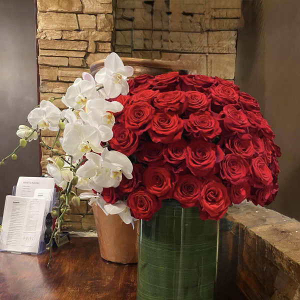 Large arrangement of red roses with white orchids in tall vases