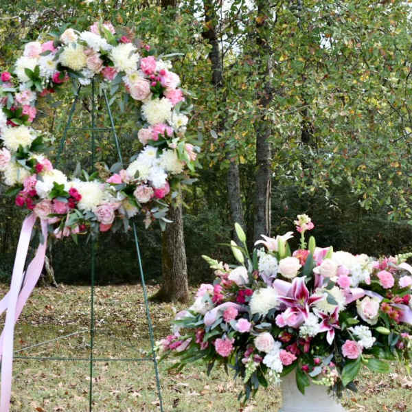 Three pink and white floral wreaths and a matching centerpiece outdoors