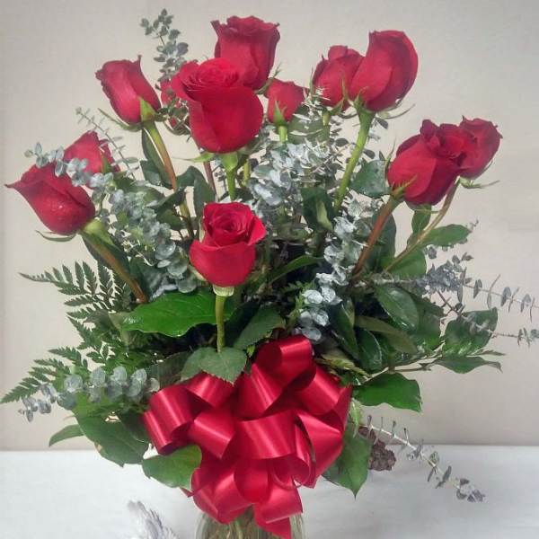 Red roses in a glass vase with a large red ribbon