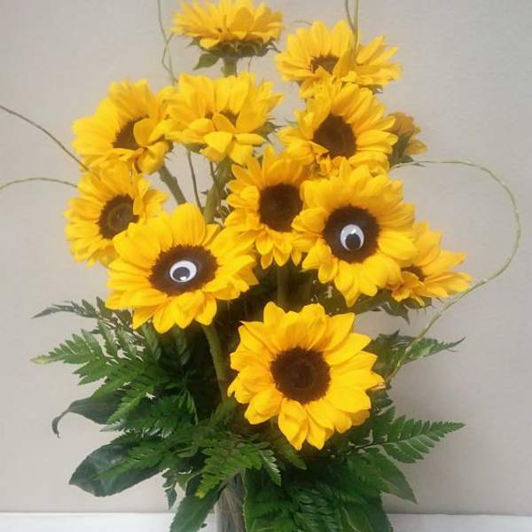 Sunflower bouquet in a glass vase with decorative googly eyes