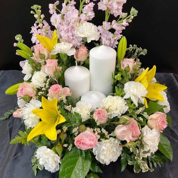 Floral candle arrangement with pink and white flowers and yellow lilies
